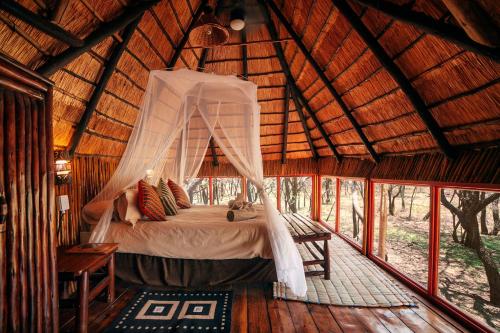 a bedroom with a bed in a straw hut at Pezulu Tree House Lodge in Hoedspruit