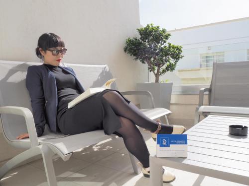 a woman sitting on a chair reading a book at Le 22 Appart'Hotel in Casablanca