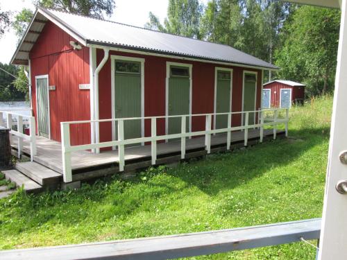 a red building with a porch on a grass field at Stöde Camping in Edsta
