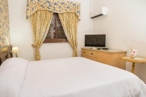 a bedroom with a white bed and a window at El Mirador Hotel & Spa in Colonia del Sacramento