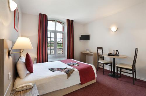 une chambre d'hôtel avec un lit, une table et une fenêtre dans l'établissement Vacancéole - Les Demeures Champenoises Confort, à Épernay