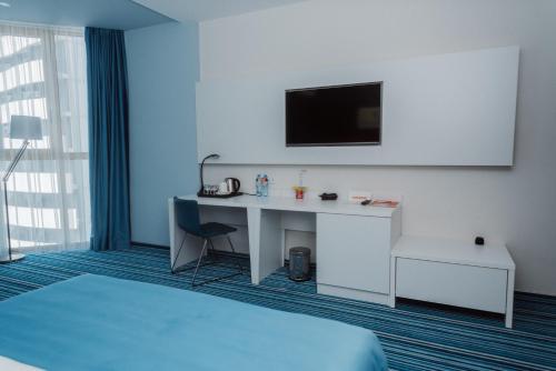 a room with a bed and a desk with a tv at Aparthotel Tangerine in Batumi