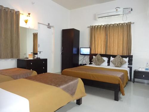 a hotel room with two beds and a television at Teerth Villa in Nashik