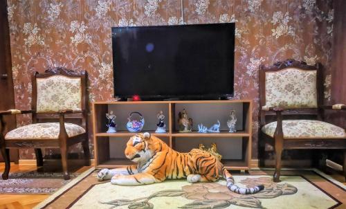 a tiger laying on the floor in front of a television at Hostel Sadu Kutaisi in Kutaisi