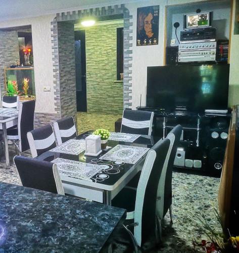 a dining room with a table and chairs and a television at Hostel Sadu Kutaisi in Kutaisi