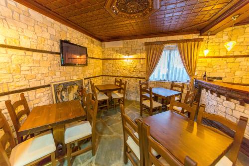 um restaurante com mesas e cadeiras de madeira e uma parede de pedra em Heraklis Hotel em Berati