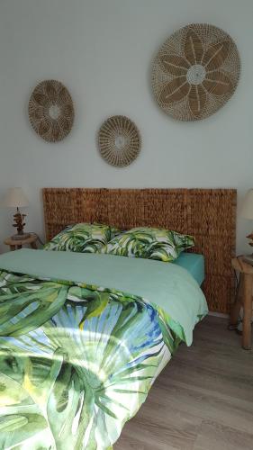 ein Bett mit einer grünen Bettdecke und zwei Ventilatoren an der Wand in der Unterkunft Au bout du Port in Le Guilvinec