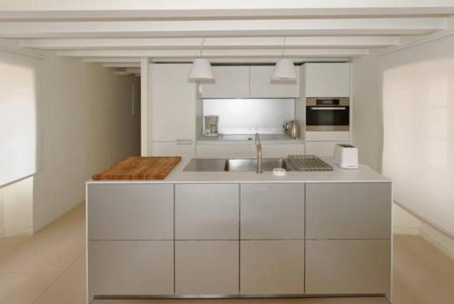 uma cozinha com armários brancos e um lavatório em L’Ile Rousse les pieds dans l’eau em L'Île-Rousse