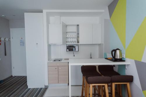 a kitchen with white cabinets and two stools at Aparthotel Tangerine in Batumi