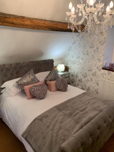 1 dormitorio con cama con almohadas y lámpara de araña en The griffin cottage en Ludlow