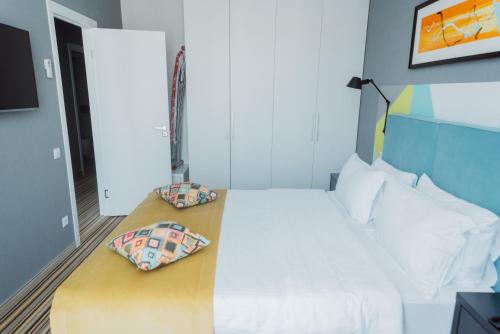a bedroom with a white bed with two pillows on it at Aparthotel Tangerine in Batumi