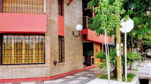un edificio en una calle con un árbol delante en Bombal Departamentos en Mendoza