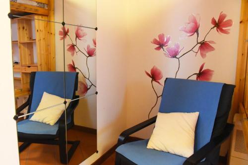 two blue chairs in a room with flowers on the wall at Cozy Garden Retrait in Varenna