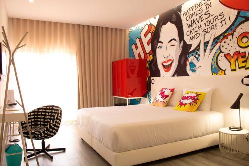 um quarto com uma cama branca e um quadro na parede em RIDE Surf Resort & Spa em Peniche