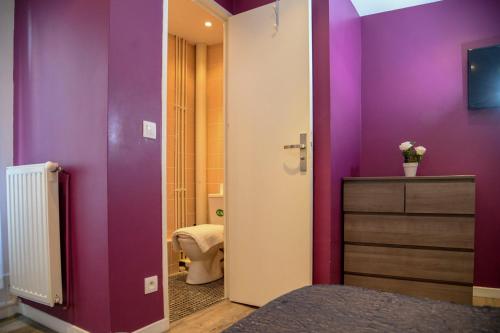 a bathroom with purple walls and a toilet in it at HOTEL HOVI DE LA MAIRIE in Aubervilliers