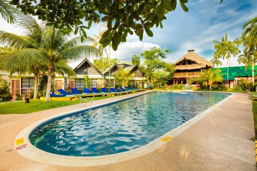 - une piscine en face d'une maison avec des palmiers dans l'établissement Decameron Decalodge Ticuna, à Leticia