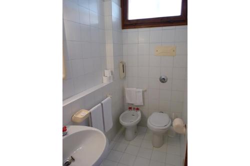 a white bathroom with a toilet and a sink at La Mitica 99 del Portolaconia Residence in Cannigione