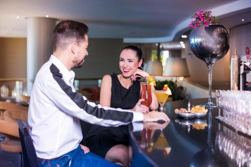 a man and a woman standing at a bar at Enotel Lido - All Inclusive in Funchal