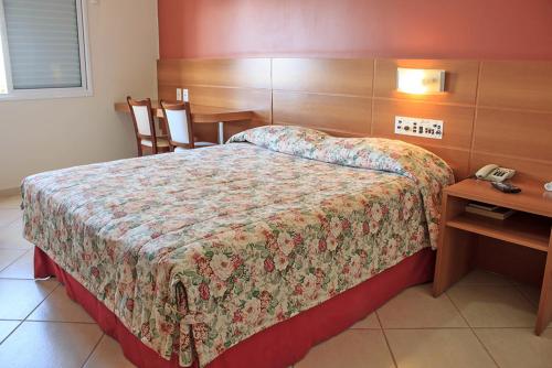 1 dormitorio con cama, mesa y teléfono en Hotel Nova York, en Araçatuba