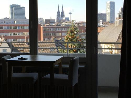 a table and chairs and a window with a view of a city at Köln Deutz/Messe, Lanxess Arena in Cologne