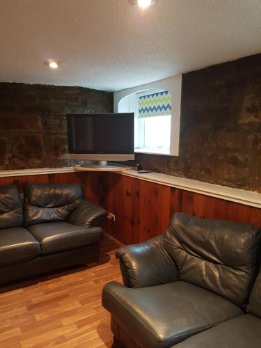 a living room with leather furniture and a flat screen tv at ladyhill flat in Elgin