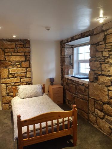 a bedroom with a bed and a stone wall at ladyhill flat in Elgin