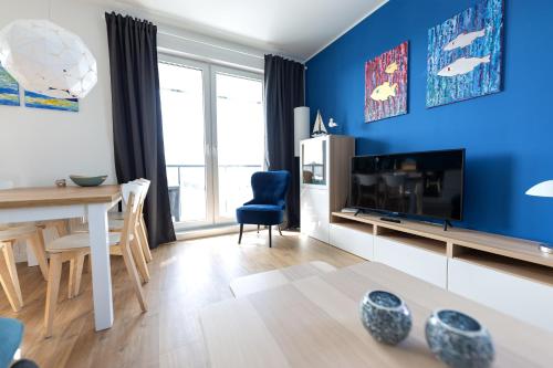 sala de estar con paredes azules, mesa y TV en Baltic Apartments Seaside Towers en Gdansk