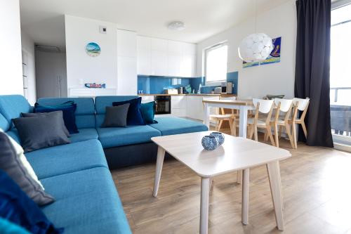 Baltic Apartments Seaside Towers في غدانسك: غرفة معيشة مع أريكة زرقاء وطاولة