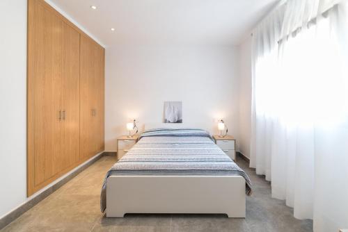 ein weißes Schlafzimmer mit einem Bett und einem Fenster in der Unterkunft Villa Margarita in L'Escala