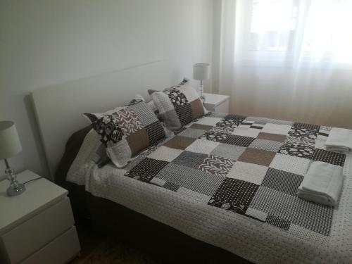 a bedroom with a bed with a checkered blanket and pillows at Casa do Pedro - Lisbon South Bay in Almada