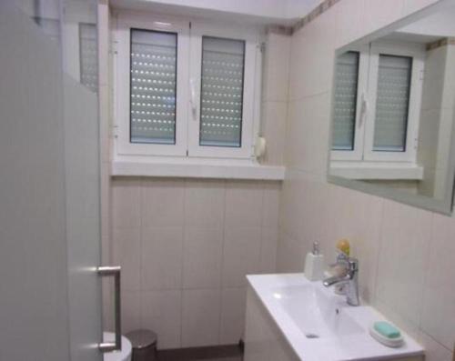 Baño blanco con lavabo y espejo en Casa do Pedro - Lisbon South Bay, en Almada