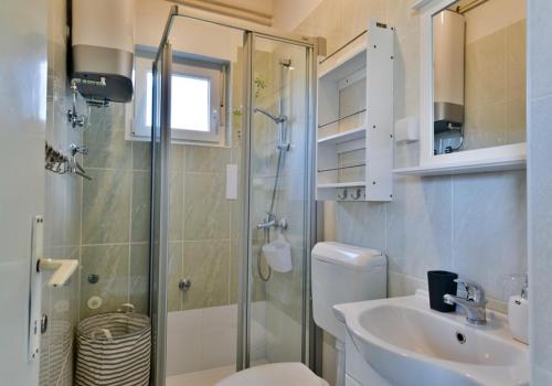een badkamer met een douche, een toilet en een wastafel bij Seafront Apartment Jadri in Umag