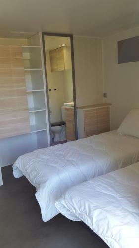 a bedroom with two white beds and a mirror at Camping Domaine du Lac Chambon in Murol