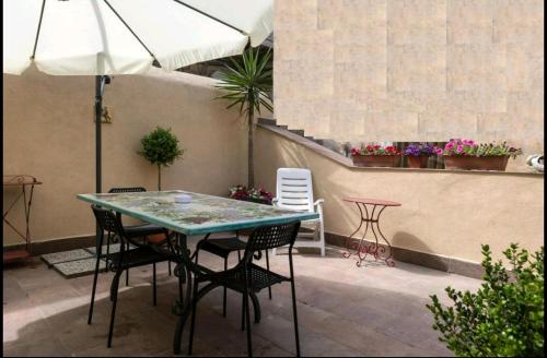 un patio con mesa, sillas y sombrilla en La casetta di Ilma, en Vietri