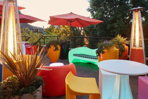 a patio with colorful chairs and tables and an umbrella at Inn at Northrup Station in Portland