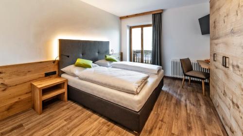 a bedroom with a bed and a desk and a chair at Hotel Garni Sonngart in Andrian