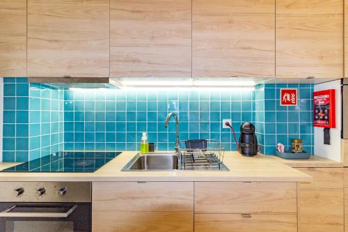a kitchen with a sink and a blue tiled wall at Cedofeita 408, Green in Porto