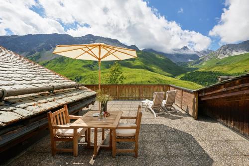 um pátio com uma mesa, cadeiras e um guarda-sol em Hotel Stoffel - adults only em Arosa