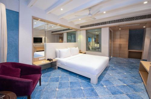 1 dormitorio con cama blanca y silla morada en Hotel Bawa Suites, en Bombay