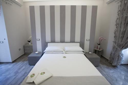 a large white bed in a room with striped walls at Le Due Sicilie in Tropea