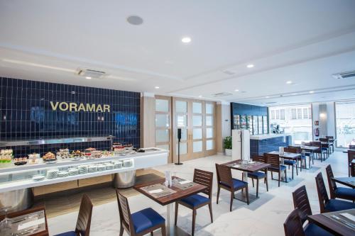 a restaurant with tables and chairs and a counter at Hotel Voramar in Benidorm
