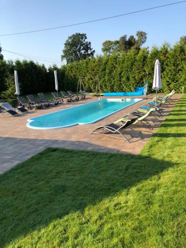 a large swimming pool with chairs and umbrellas at Mazurski Komfort in Piecki