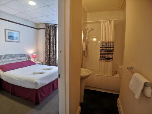 a bedroom with a bed and a bathroom with a shower at The Hopton Hotel in Blackpool