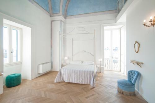 a white bedroom with a bed and a blue chair at Relais Monastero Santa Teresa - Albergo Diffuso in Nardò