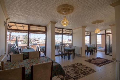 a dining room with tables and chairs and windows at Kamelya Cave Hostel in Goreme