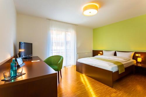 Schlafzimmer mit einem Bett und einem Schreibtisch mit einem Computer in der Unterkunft ACANTUS Hotel in Weisendorf