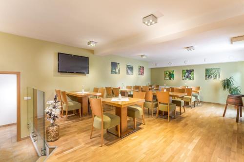 a restaurant with tables and chairs and a flat screen tv at Penzion a vinařství U Vrbů in Hustopeče
