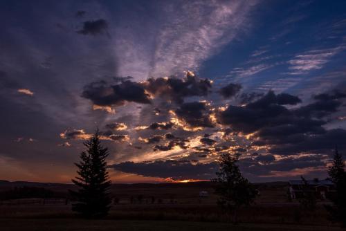 a cloudy sky at sunset with trees in a field at Rocky Ridge Country Lodge in Mountain View