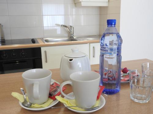 a table with two cups and a bottle of water at Hill View Hotel Apartments in Pissouri