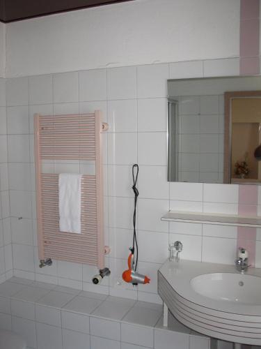 a white bathroom with a sink and a mirror at Hotel Restaurant Escher in Leukerbad